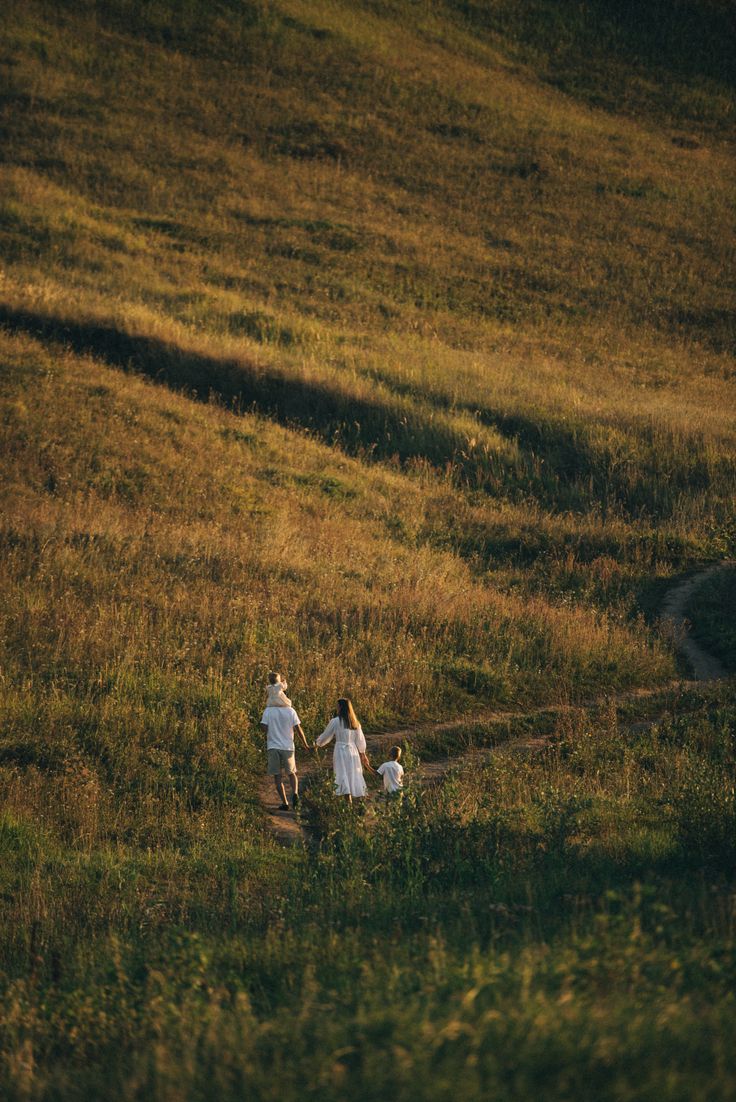 Family walking together through a hilly meadow at golden hour